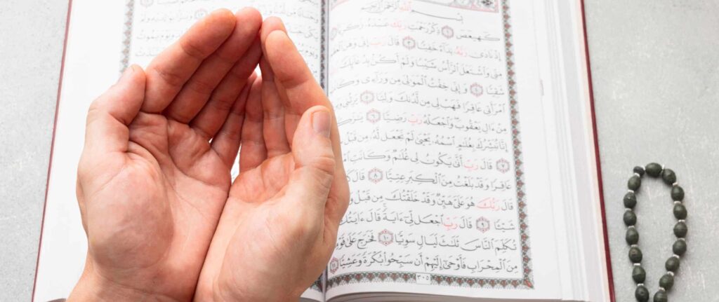 tangan muslim berdoa di depan Qur’an