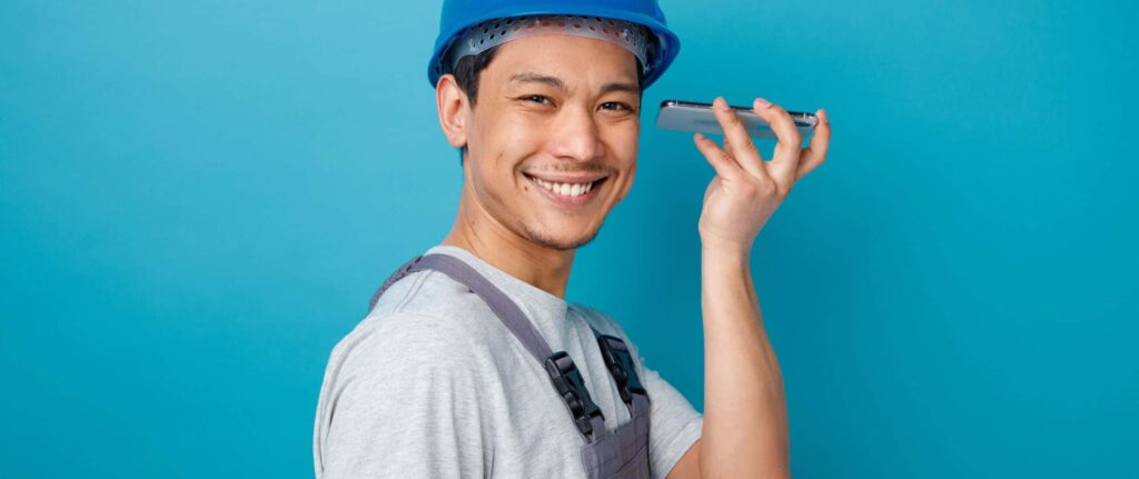 teknisi yang tersenyum sambil menerima telepon