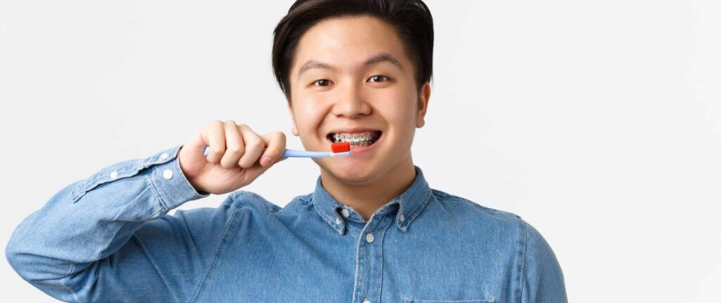 orang yang tersenyum sambil menyikat gigi