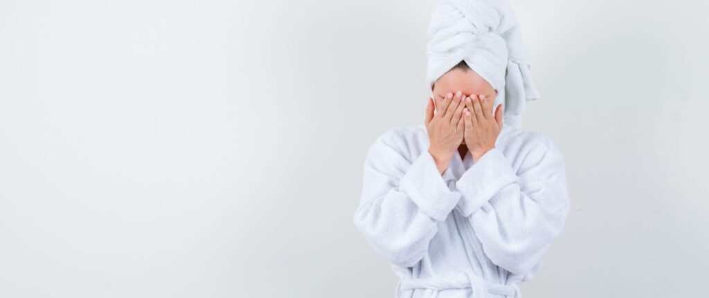 orang yang memakai handuk sambil menutup wajah