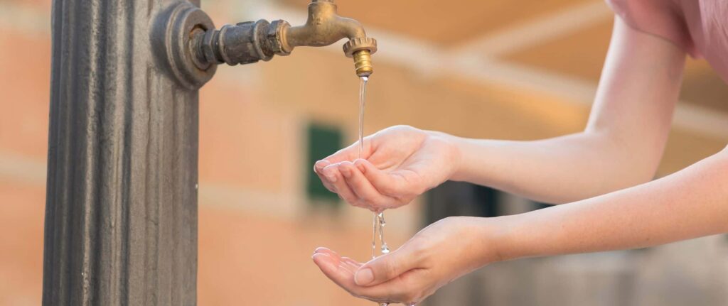 tangan menengadah di bawah air keran