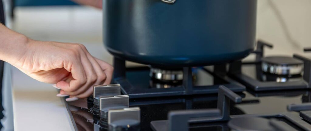 seorang wanita sedang menyalakan kompor gas