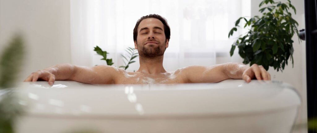 seorang pria berendam di dalam bathtub sambil memejamkan mata seorang pria berendam di dalam bathtub sambil memejamkan mata