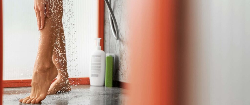 wanita sedang menyiram kaki memakai air dari shower wanita sedang menyiram kaki memakai air dari shower