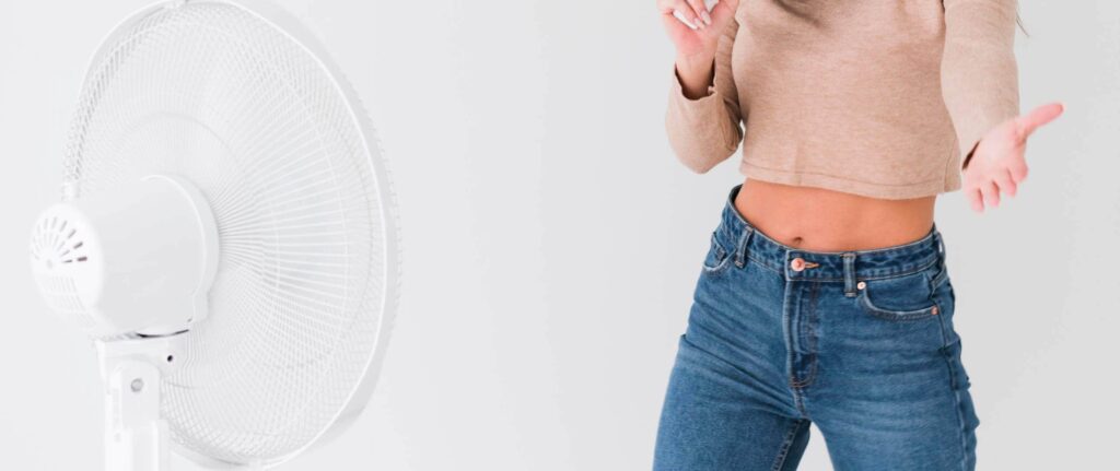 orang yang mengarahkan kipas angin langsung ke badan sambil berdiri