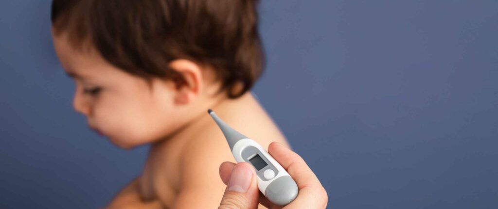 bayi duduk dan disampingnya seseorang sedang memegang termometer bayi duduk dan disampingnya seseorang sedang memegang termometer