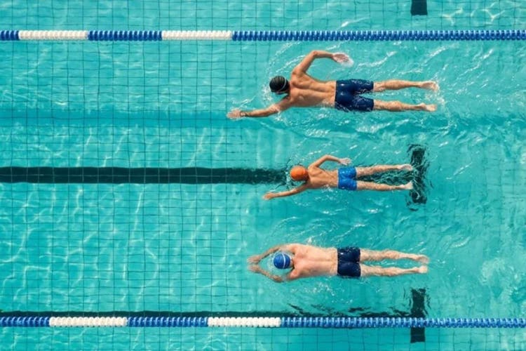 Tiga pria berbagai usia berenang di outdoor pool
