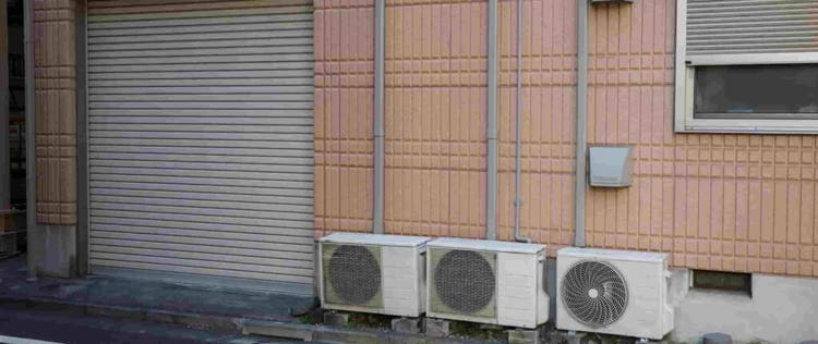 tiga unit AC outdoor berjejer di dinding bangunan