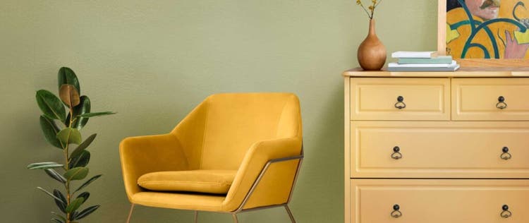 dinding warna sage dengan nakas warna kuning dan kursi kuning mustard