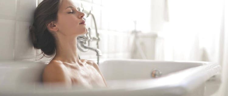 seorang wanita bersandar di bathtub sambil memejamkan mata