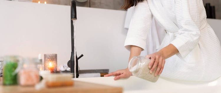 seorang wanita menuangkan garam mandi ke dalam bathtub