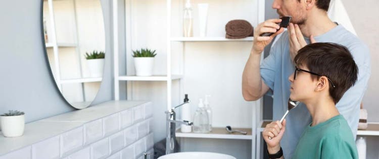 ayah dan anak sedang menggunakan alat cukur di kamar mandi