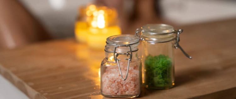 wanita mandi dengan garam mandi dan lilin aromaterapi di atas bathtub