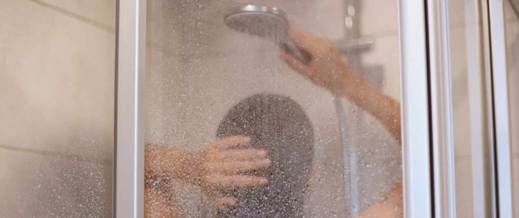 wanita sedang mandi air hangat pakai shower