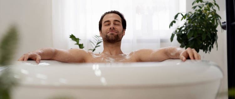 seorang pria berendam di dalam bathtub sambil memejamkan mata